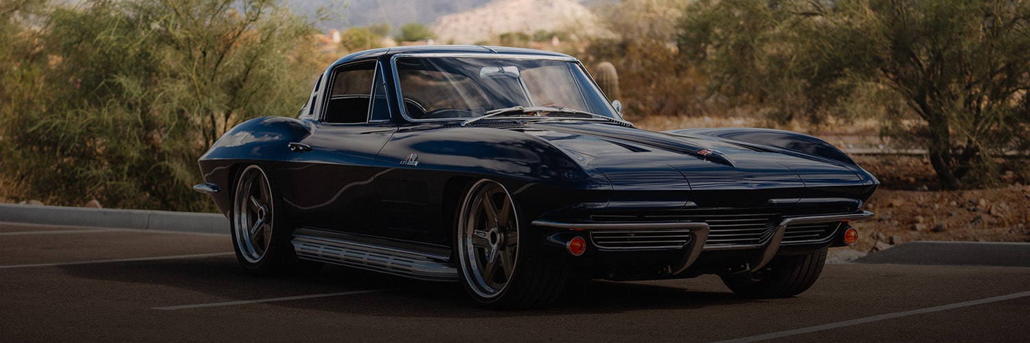 A Dark Blue Classic Chevrolet Corvette Stingray Coupe Parked on a Road With Desert Vegetation in the Background and Text Reading “Performance Optimized.”
