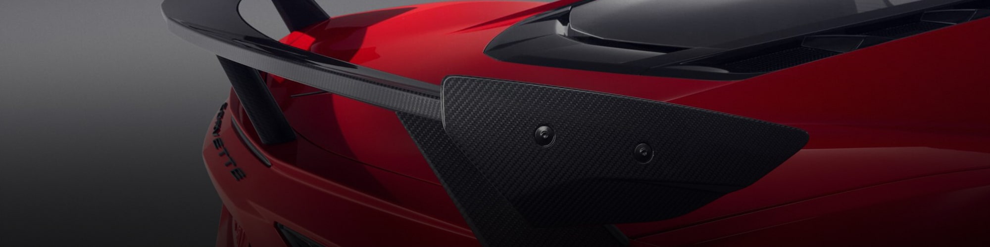A Close-Up of a Red Chevrolet Corvette Rear Spoiler with Visible Carbon Fiber Texture and Aerodynamic Design.