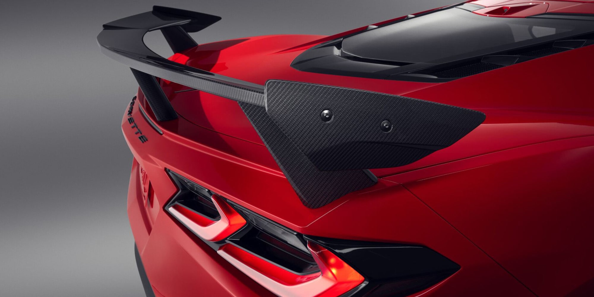 A Rear View of a Red Chevrolet Corvette Featuring a Large Carbon Fiber Rear Wing and Aggressive Styling Elements.