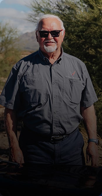 One Person Standing Outdoors With Greenery in the Background and White Text Overlay Reading “I’m a Diehard Chevrolet Guy, No Doubt About That.” With the Name Barry Blomquist and “1966 Corvette” Below.