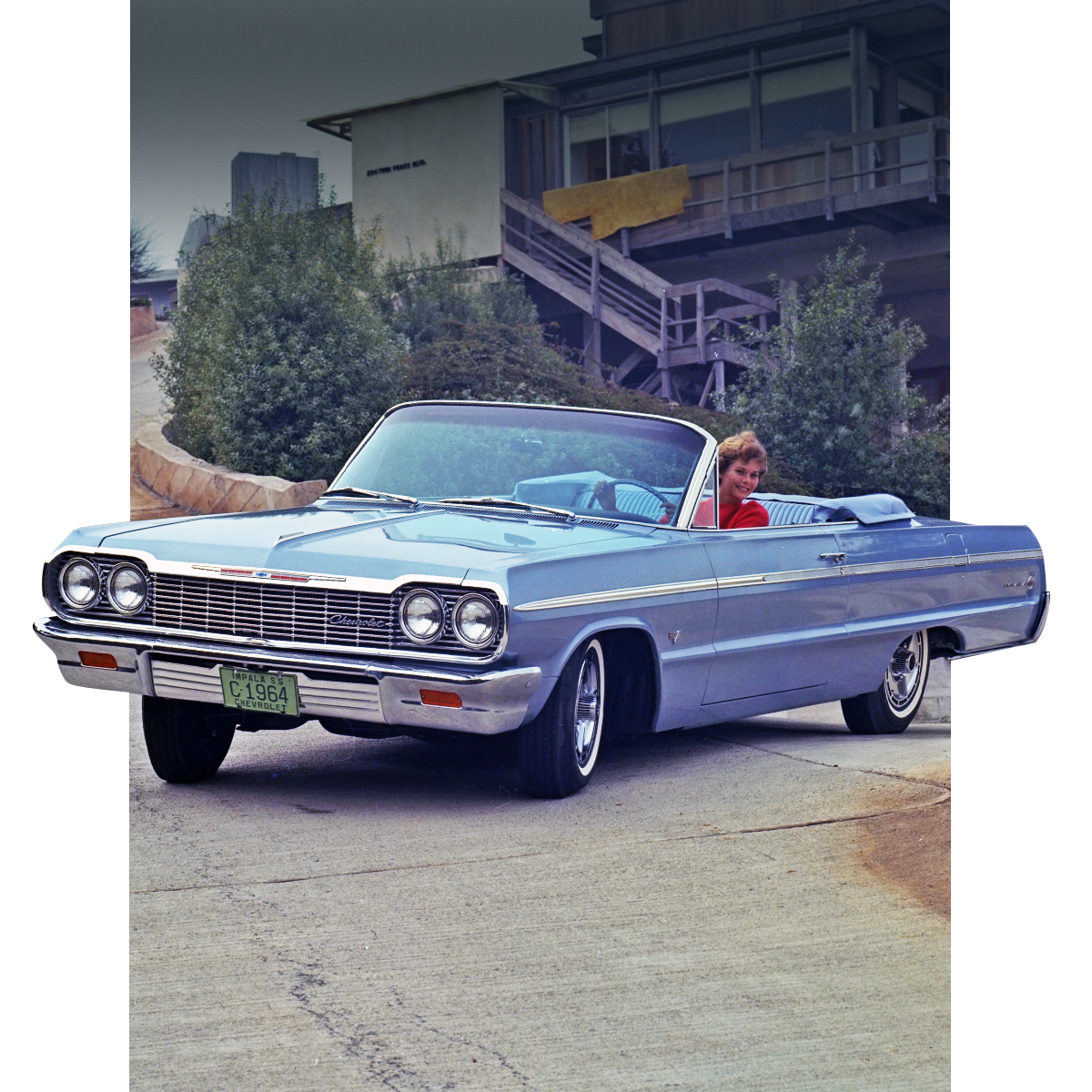 Front Three-Quarter View on a Driveway of a Classic Light Blue Chevrolet Impala with Driver