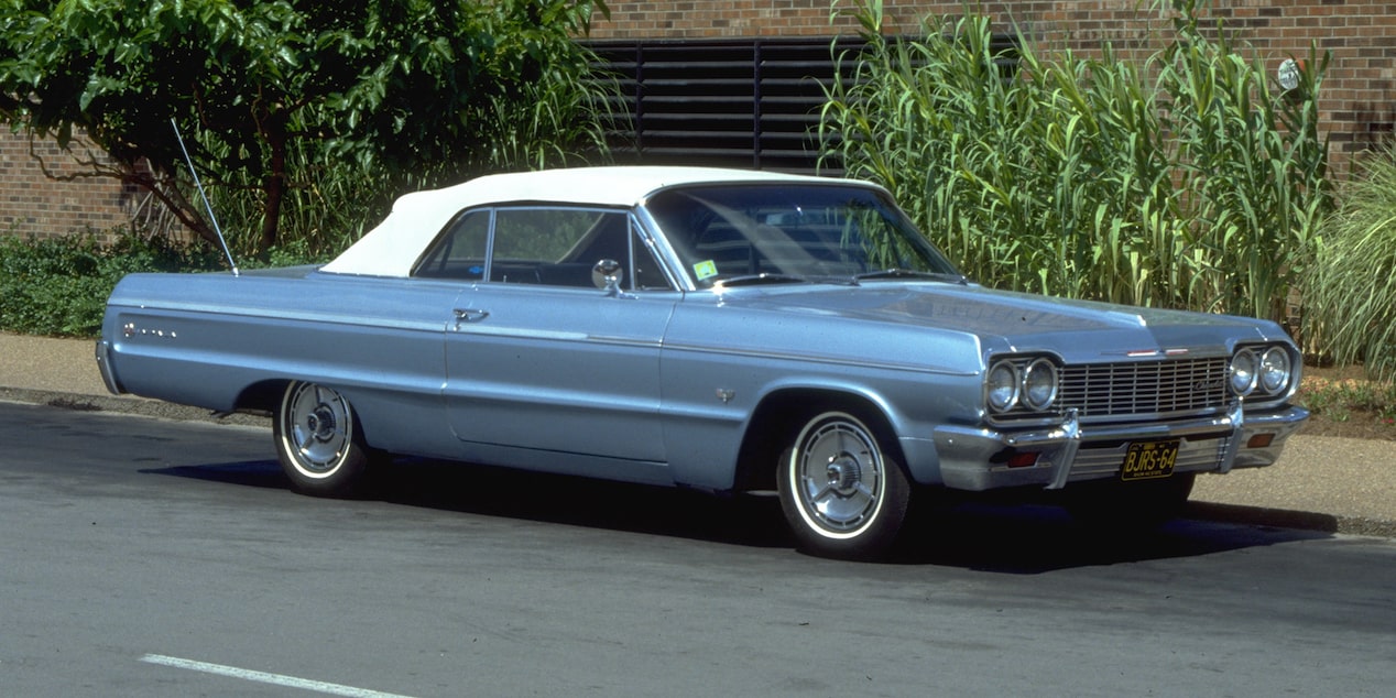 Chevrolet Impala blanco con techo rojo exhibido sobre un fondo rojo sólido.