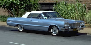 Chevrolet Impala blanco con techo rojo exhibido sobre un fondo rojo sólido.