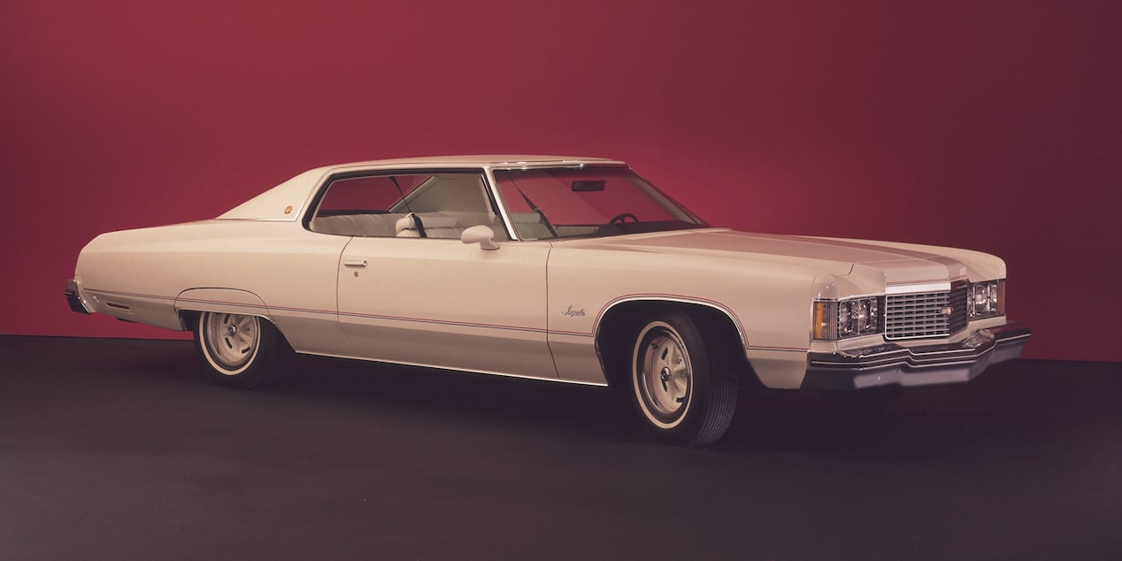 Chevrolet Impala blanco con techo rojo posicionado sobre un fondo rojo sólido.