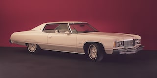 Chevrolet Impala blanco con techo rojo posicionado sobre un fondo rojo sólido.