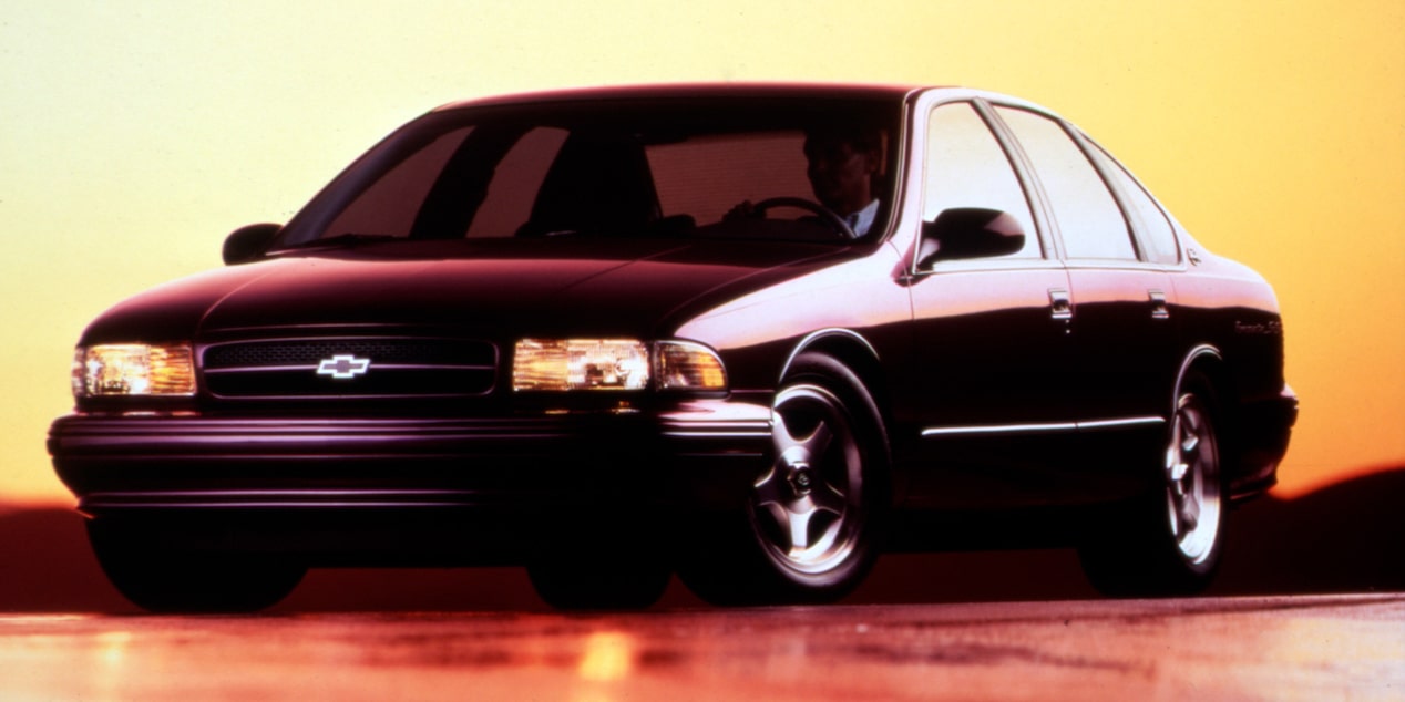 Chevrolet Impala negro mostrado de perfil sobre un fondo naranja, con sombras marcadas.