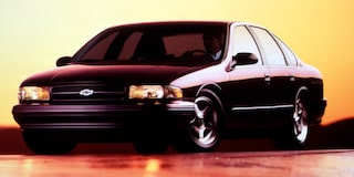 Chevrolet Impala negro mostrado de perfil sobre un fondo naranja, con sombras marcadas.