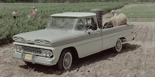 A Beige Chevrolet Silverado 1500 Pickup Truck Parked on a Dirt Path Surrounded by Grass and Wildflowers.