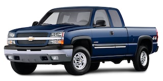 A Blue Chevrolet Silverado 2500 4x4 Pickup Truck Parked on a Road With Green Trees in the Background.