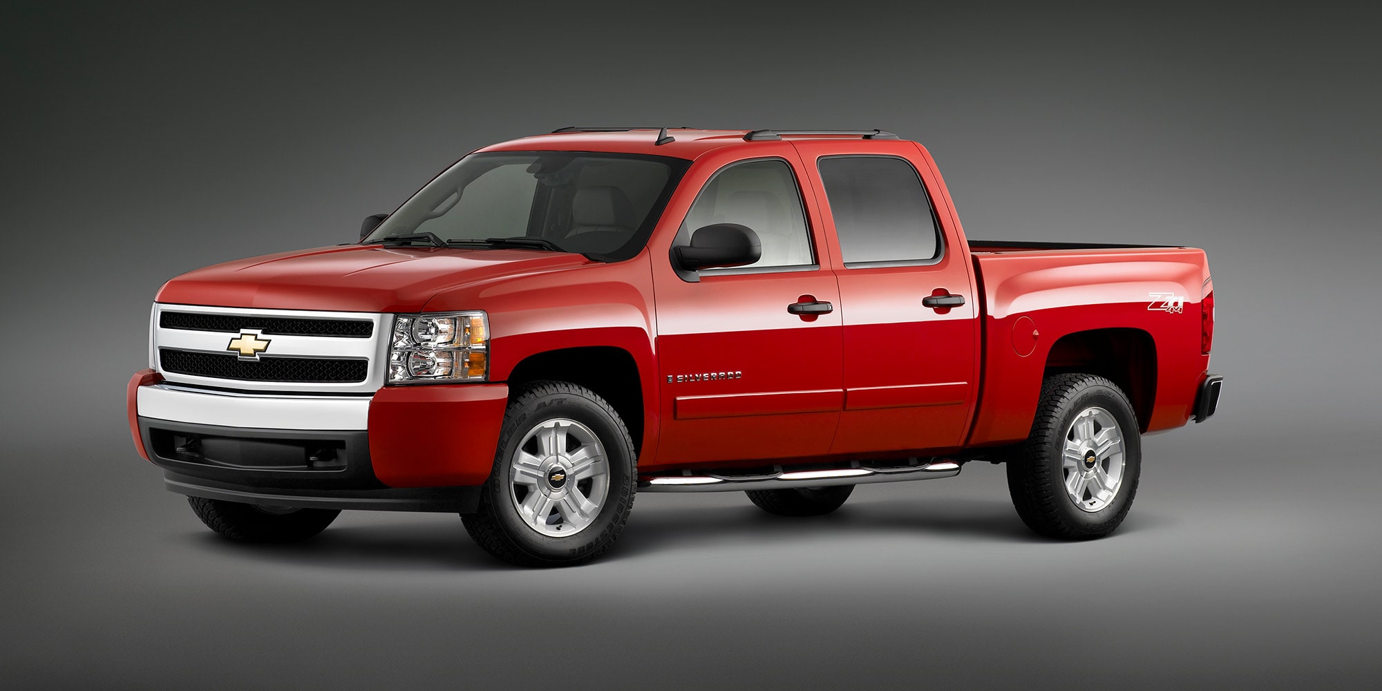 A Red Chevrolet Silverado 1500 4x4 With Z71 Package Parked on a Gray Surface With a Neutral Background.
