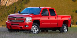 A Red Chevrolet Silverado 2500HD 4x4 With Z71 Package Parked on a Dirt Road With a Rocky Hill and Blue Sky in the Background.