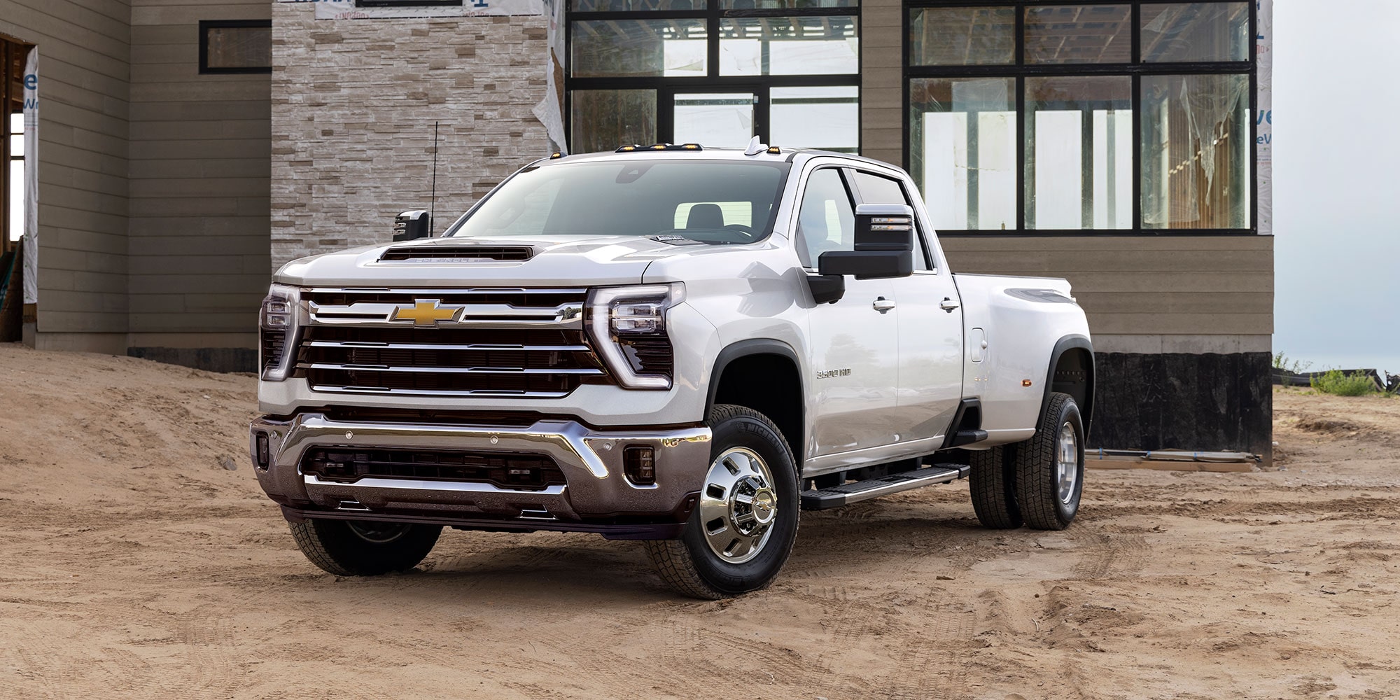 A White Chevrolet Silverado EV Parked in Front of a Contemporary House With Stone and Wood Exterior Design.