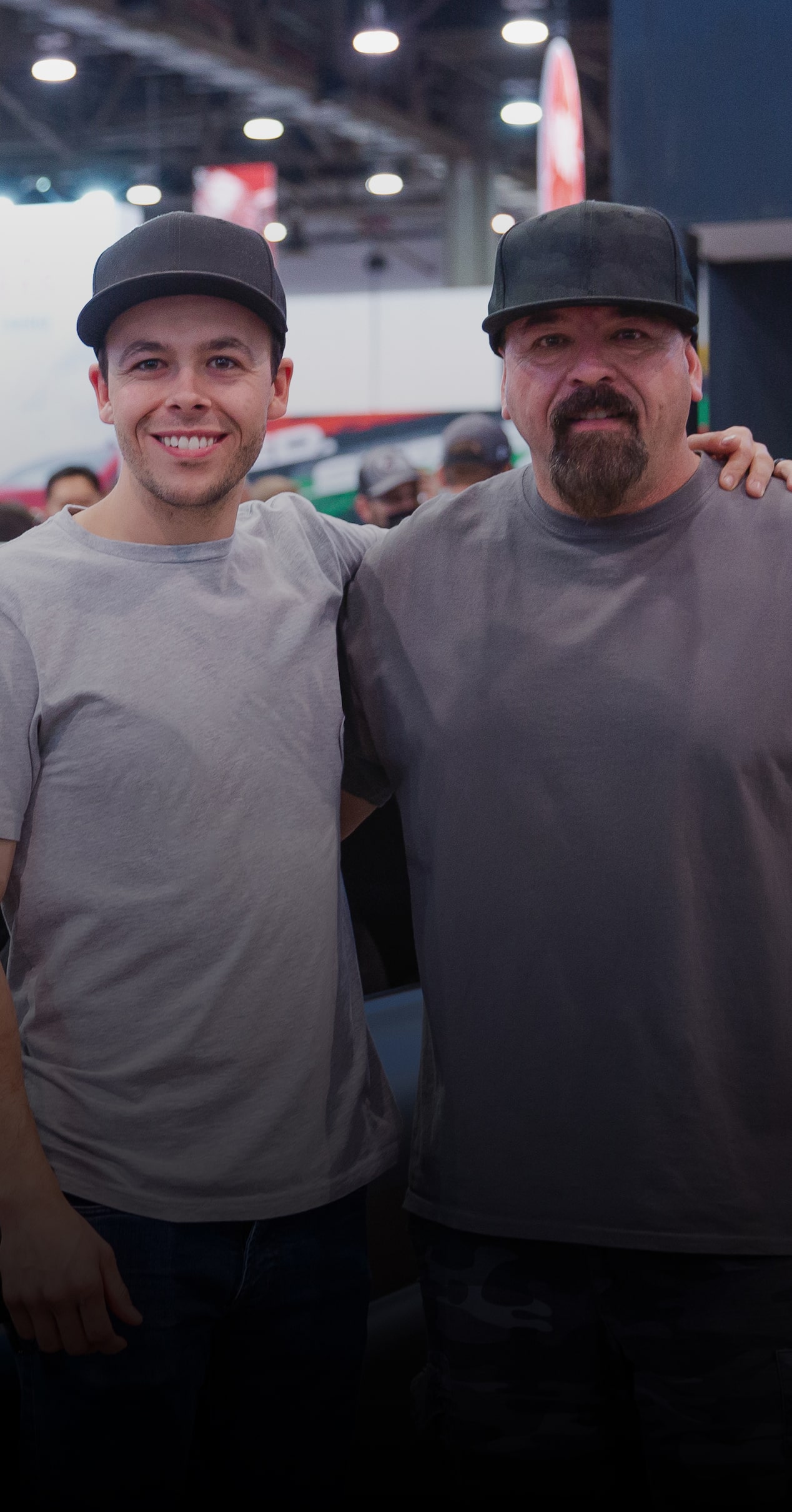 A Person Wearing a Gray DeBerti Logo T-Shirt Standing Beside Another Person Wearing a Dark Shirt with Visible Text That Reads We Like Building Crazy Stuff Above the Names Brad and Doug DeBerti and C10 Slayer 1965 Chevrolet C10.