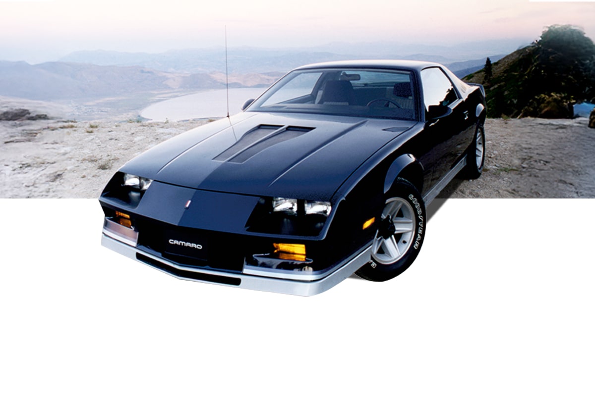 Black Chevrolet Camaro Vehicle Parked on a Mountain Overlook with a Lake and Distant Hills in the Background
