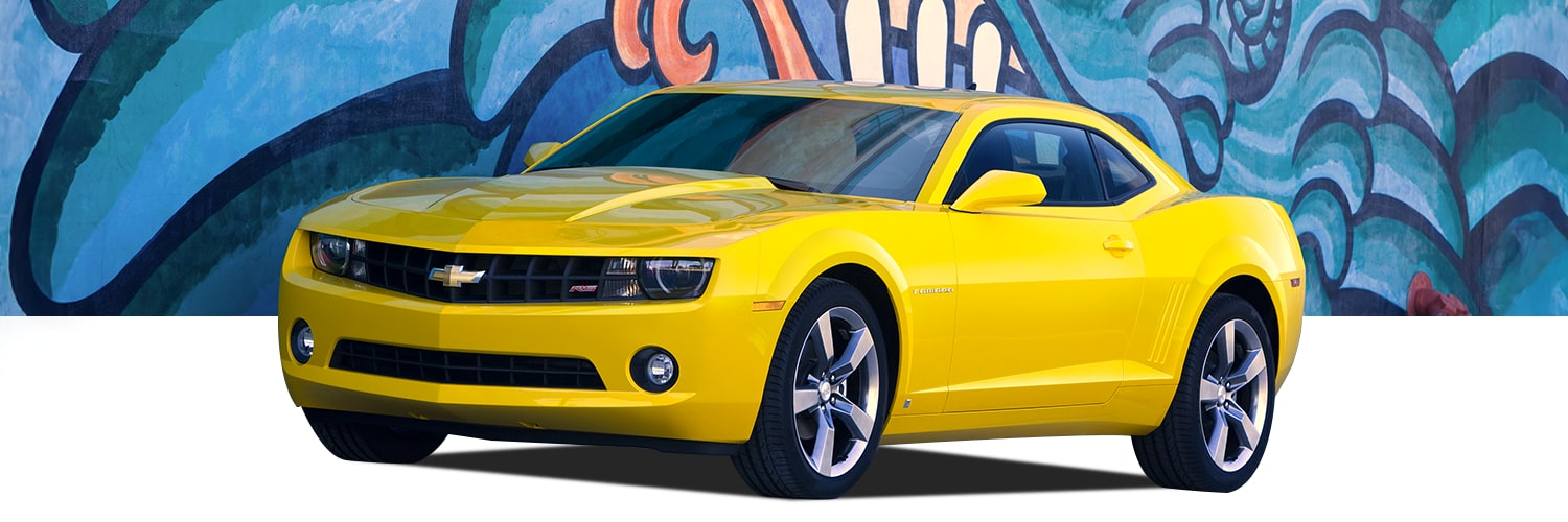 Yellow Chevrolet Camaro Coupe Front Three-Quarter View Parked in Front of a Colorful Artwork Filled Wall