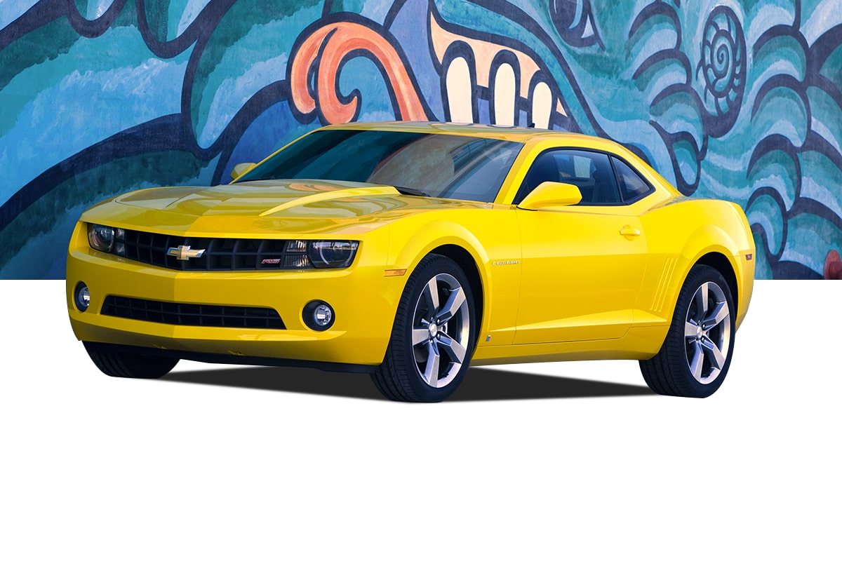 Yellow Chevrolet Camaro Coupe Front Three-Quarter View Parked in Front of a Colorful Artwork Filled Wall
