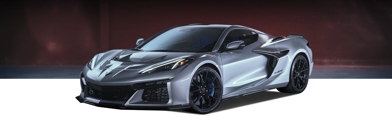 A Silver Chevrolet Corvette Z06 Sports Car with Black Accents, Aerodynamic Body Styling, and Glossy Black Wheels Positioned Against a Dark Background.