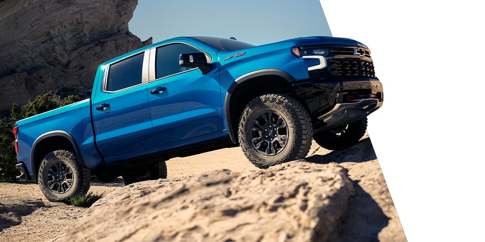 Bright Blue Chevy Silverado Pickup Truck Climbing Over Rocky Desert Terrain