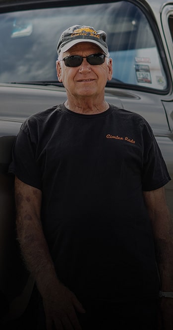 Photo of a Man Wearing Black Sunglasses and T-Shirt in Front of a Vehicle
