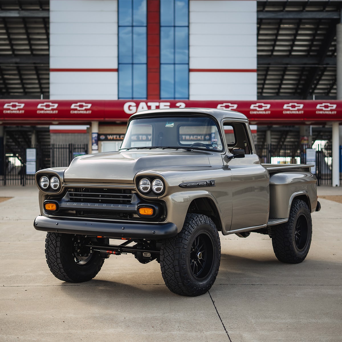 Classic Lifted Chevy Pickup Truck with Black Wheels Parked in Front of a Red and White Chevrolet Gate 3 Entrance