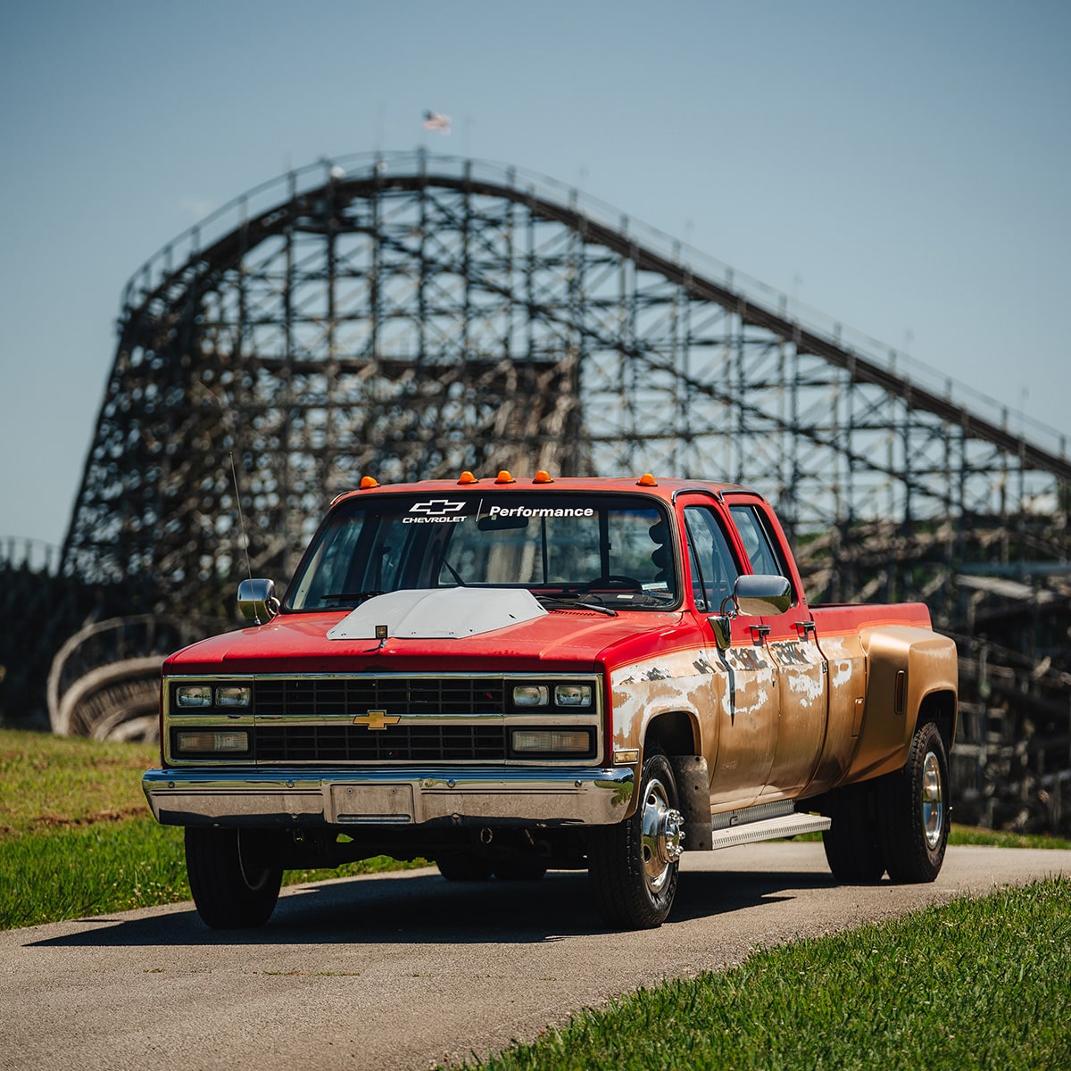 Thre-quarter View of a Classic Red and Tan Chevy Pickup Truck with a Wooden Roller Coaster in the Background