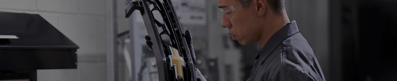 Technician Working Beside Vehicle Lift Inside Dealer Workshop