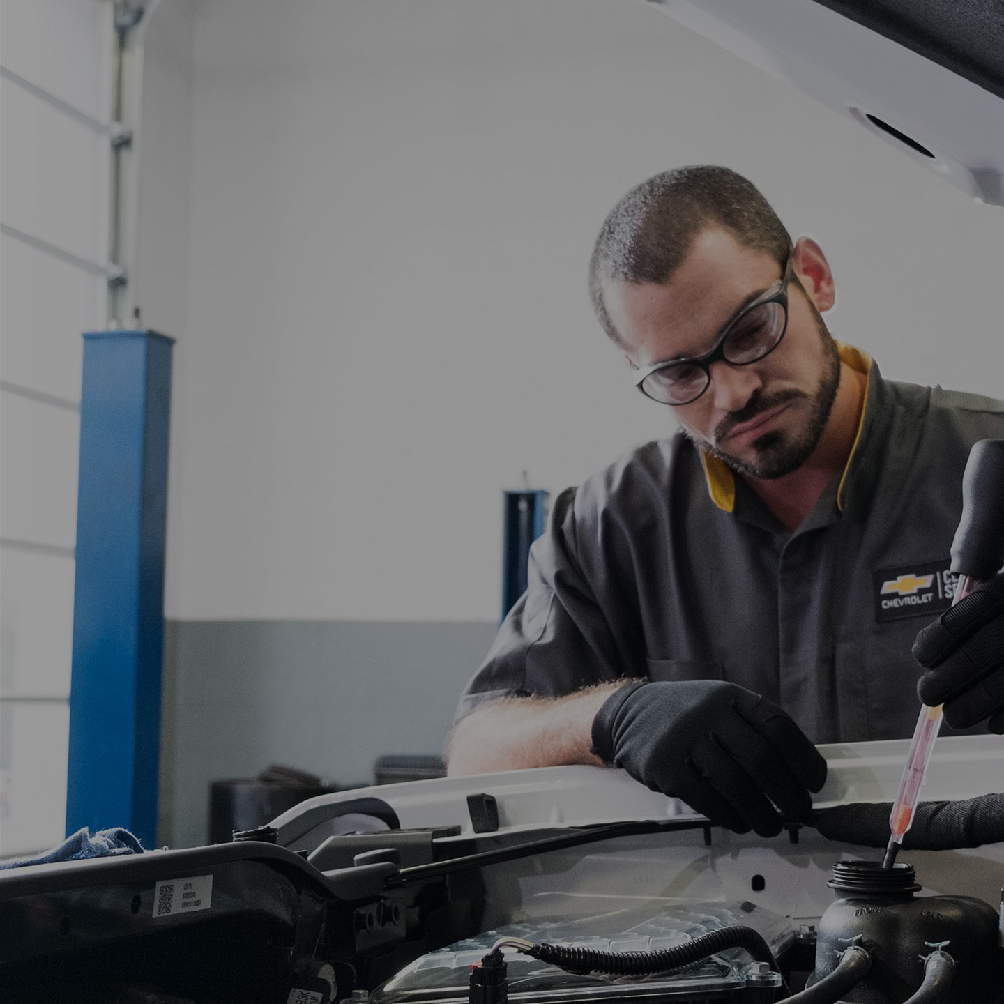 Technician Inspecting Engine Bay Components under Raised Vehicle Hood