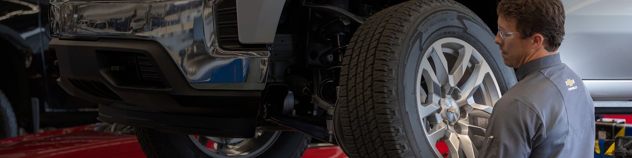 Technician Working on Front Left Tire of Vehicle in Service Bay