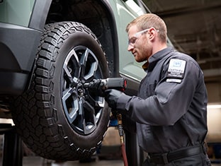 A Certified Technician Installing a New Tire on a Raised Vehicle