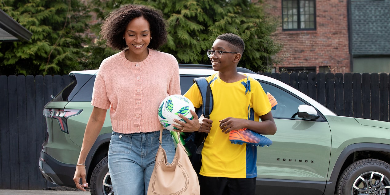 A Woman and a Boy Smiling and Walking Away from a Vehicle