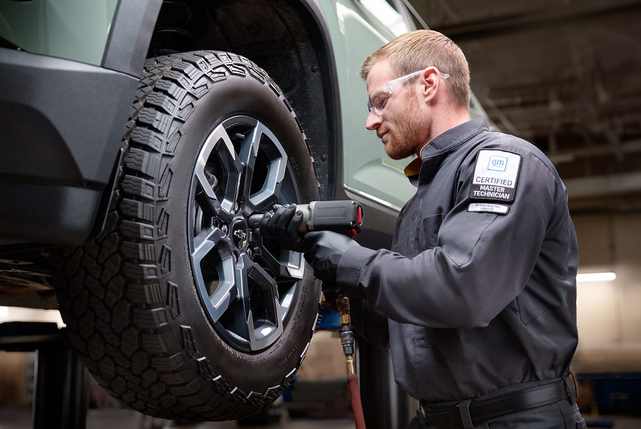 A Certified Technician Installing a New Tire on a Raised Vehicle