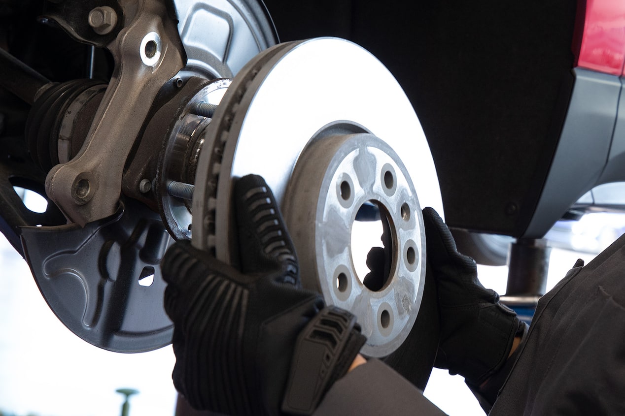 A Mechanic Wearing Black Gloves Is Placing a Metal Wheel in a Vehicle