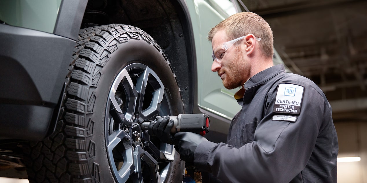 A Certified Technician Installing a New Tire on a Raised Vehicle