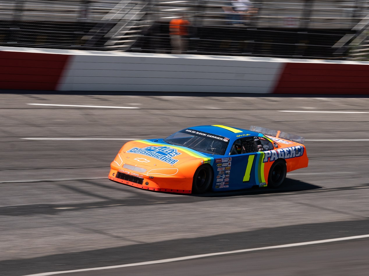 An Orange, Blue, and Yellow Racecar Blazes Down a Racetrack