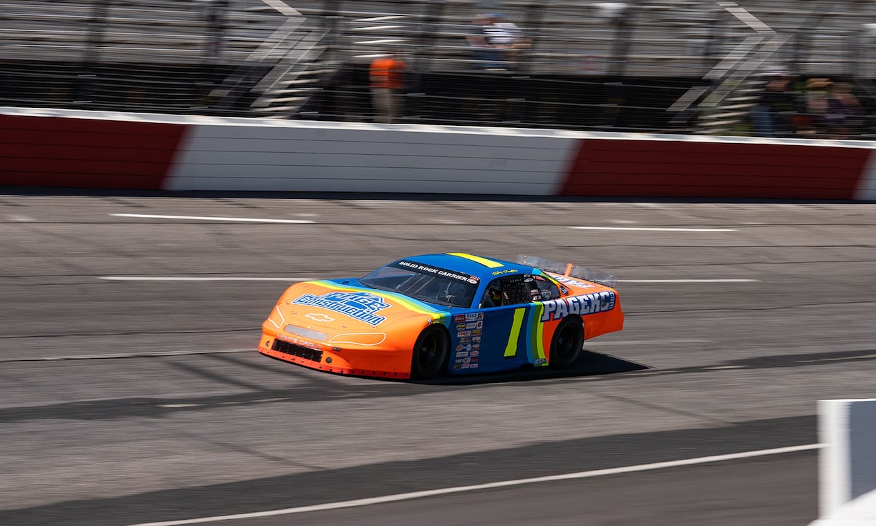 An Orange, Blue, and Yellow Racecar Blazes Down a Racetrack