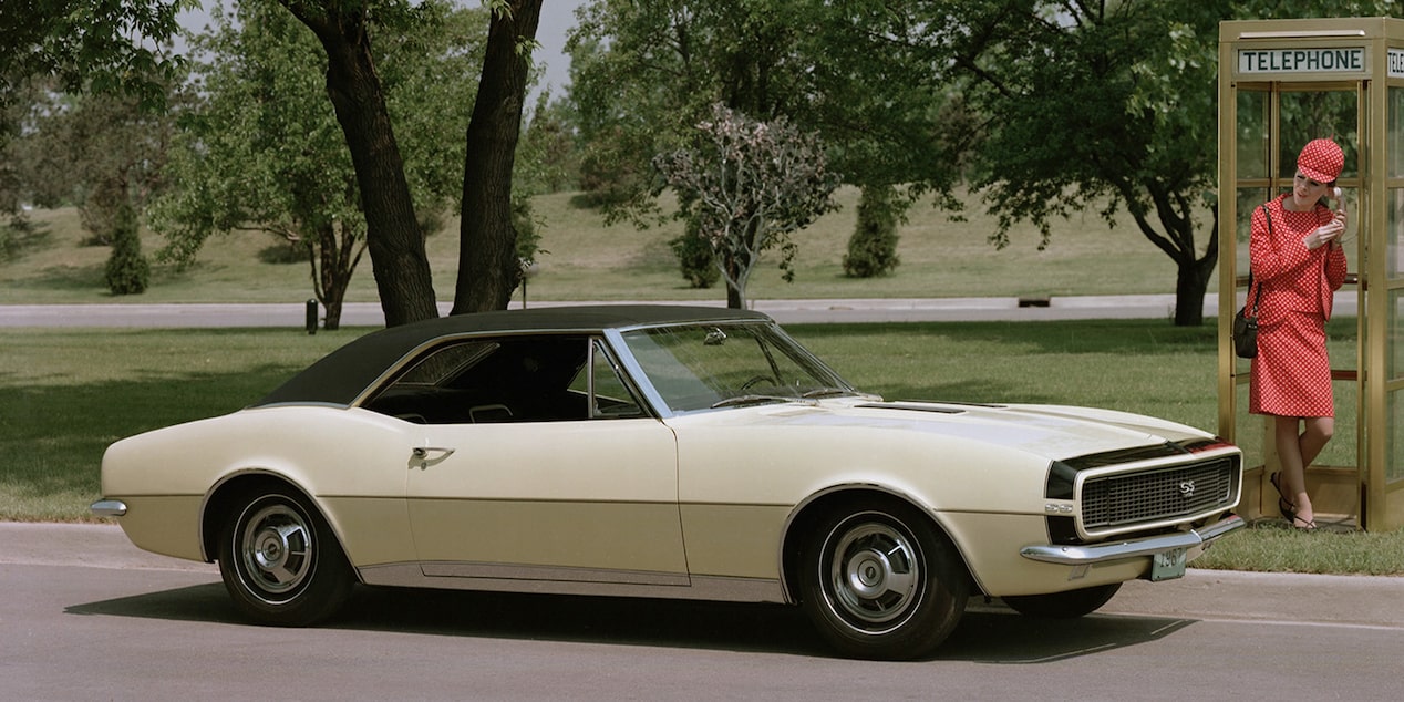 A 1967 Chevrolet Camaro SS Parked Outside a Phone Booth with a Orange-Clad Man Inside
