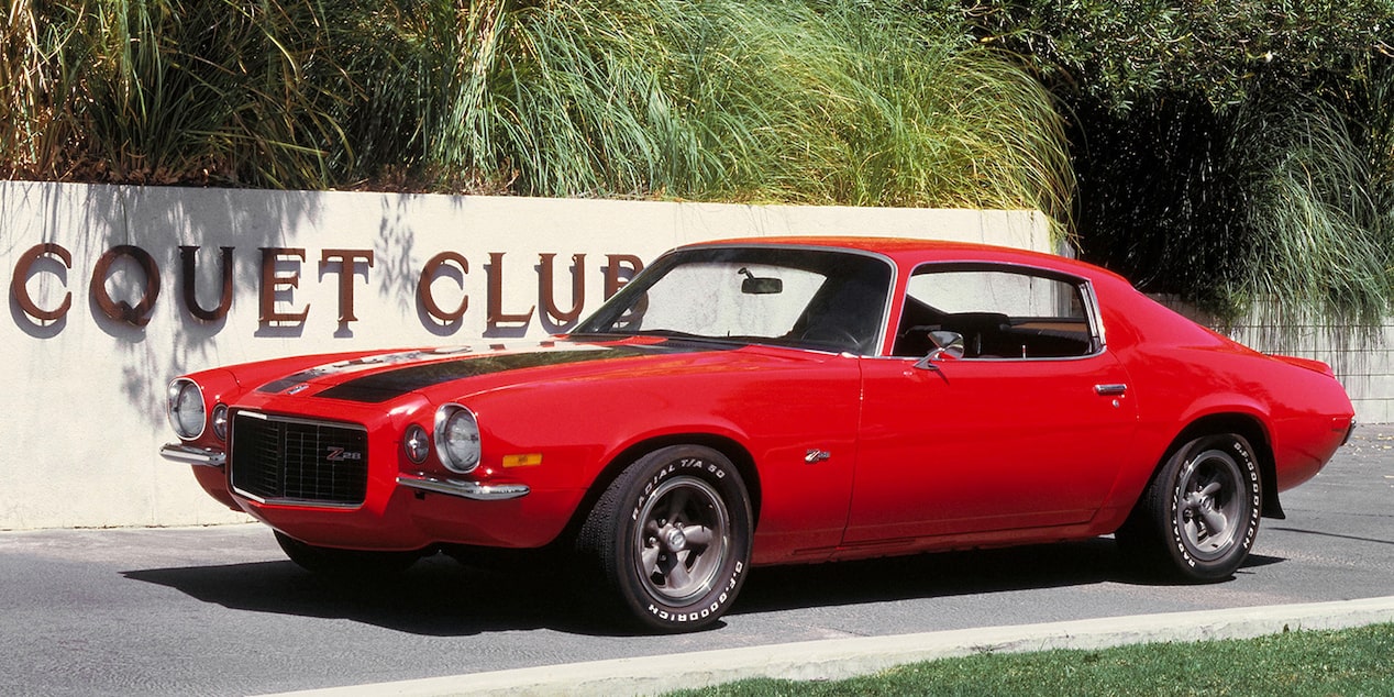A Red 1970 Chevy Camaro Parked in Front of a Sign that Reads "Racquet Club"