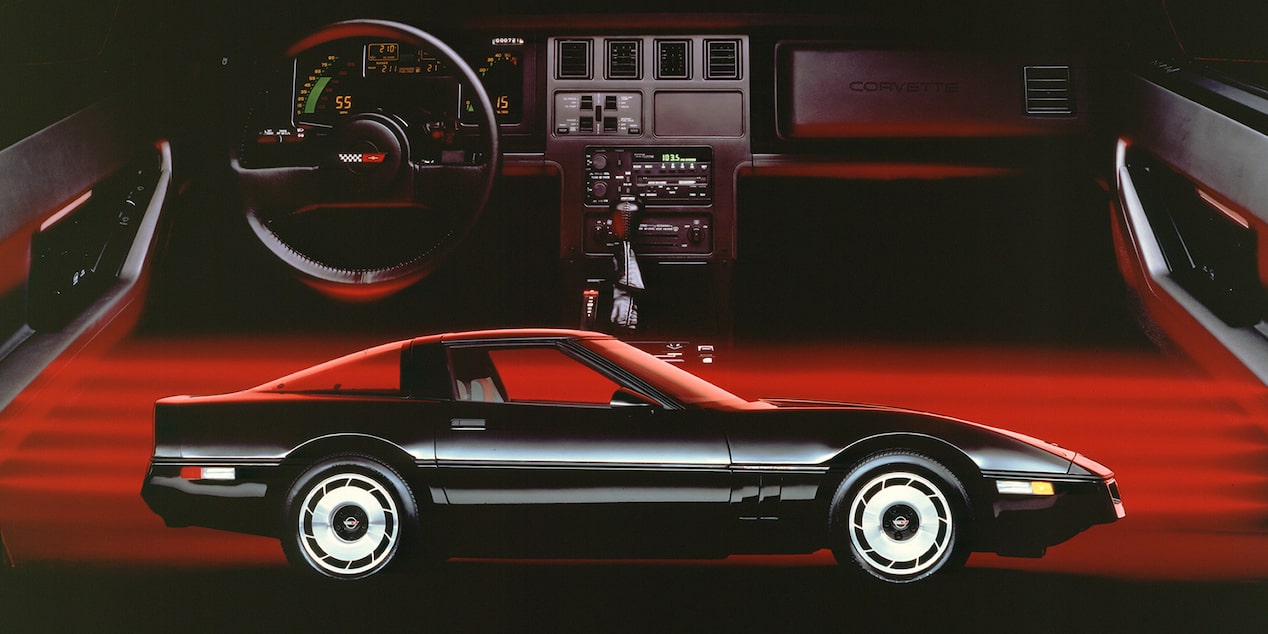 A Side View of a Black 1985 Chevrolet Corvette Coupe with Its Interior Pictured Behind It