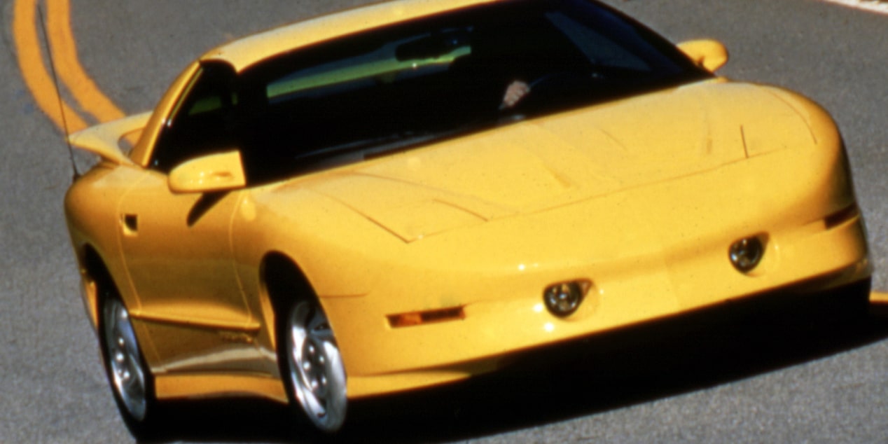 A Yellow 1993 Pontiac Firebird Trans Am Zipping Down a Curved Road