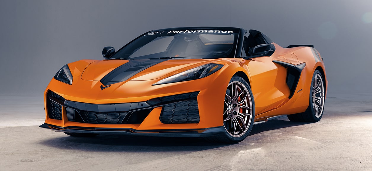 Front Three Quarters View of an Orange Chevrolet Corvette Parked on Concrete with a Grey Background