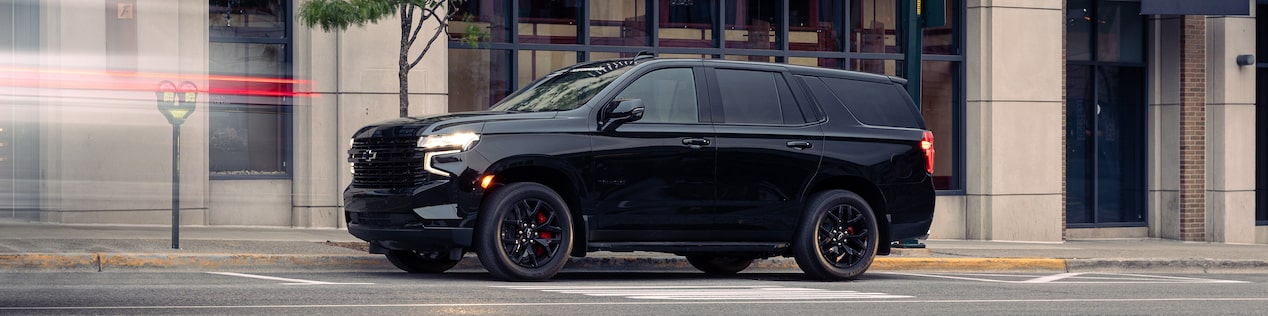 Side View of a Black Chevrolet Tahoe Parked on a City Street in Front of a Building