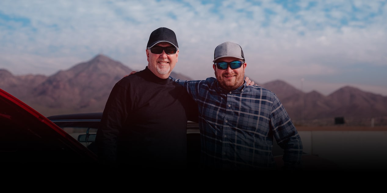 Two Men Pose in Front of a Red Chevrolet Sports Car with the Hood Open