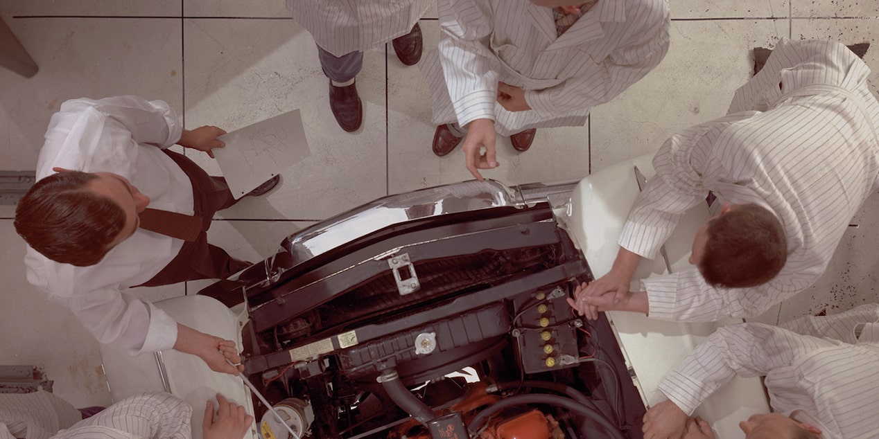 Overhead View of Engineers in White Lab Coats Look at an Engine