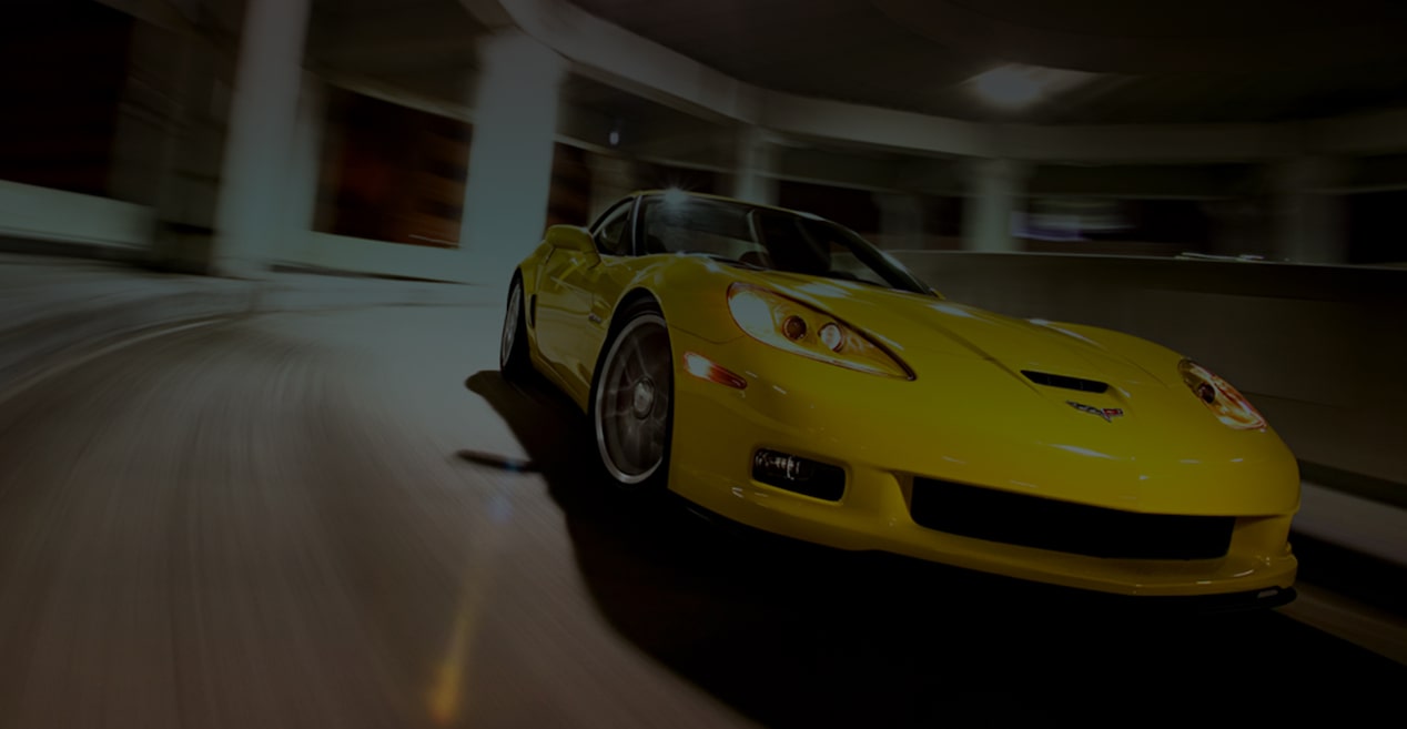 A Yellow Chevy Sportscar Taking a Curve Through a Transit Tunnel with an Overhead Light Above