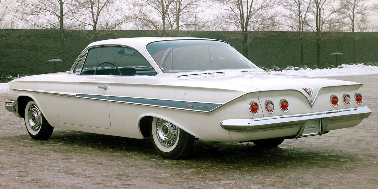 Rear Three Quarters View of a White 1961 Chevy Impala SS Parked in Front of Trees
