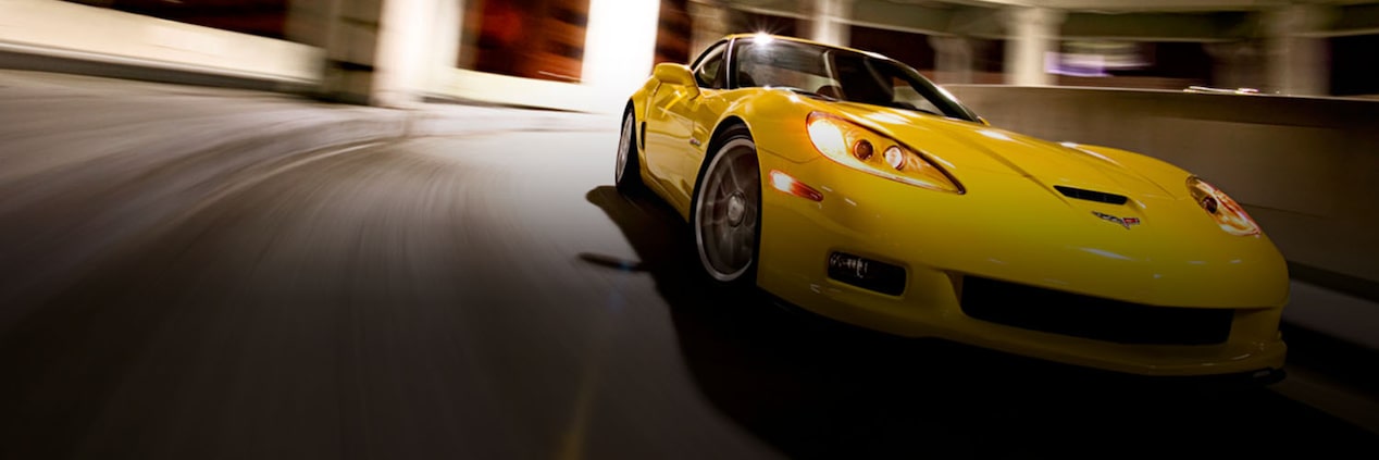 A Yellow Chevy Sportscar Taking a Curve Through a Transit Tunnel with an Overhead Light Above