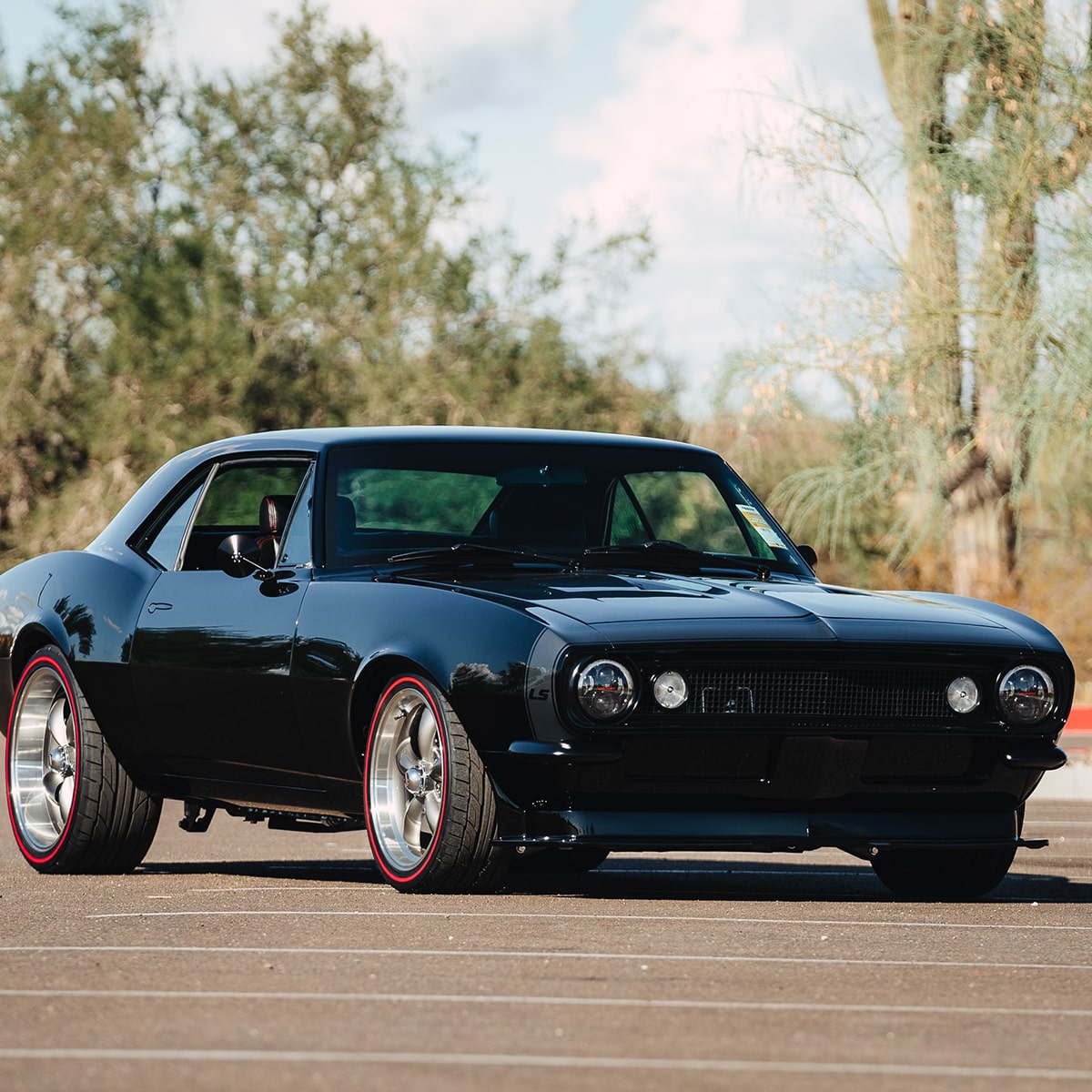 Front Three Quarters View of a Black 1967 Chevy Camaro in a Parking Lot with a Cactus in the Background