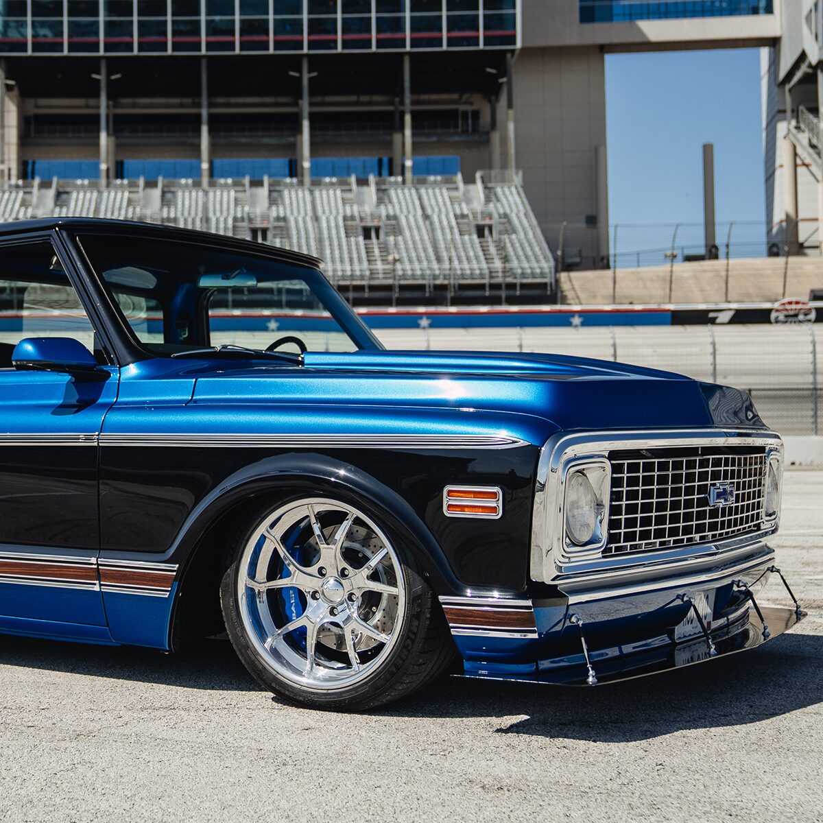 Right Side View of a Blue and Black 1972 Chevy C10 Bruzer Pickup Truck Parked at a Racetrack