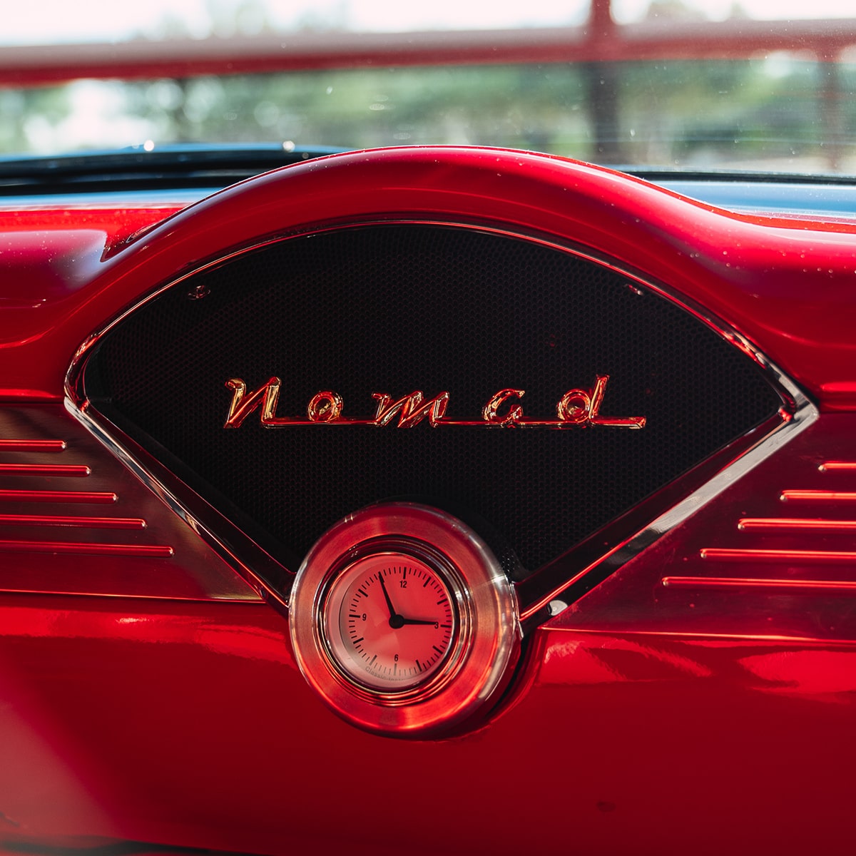 Glossy Red Dashboard of a 1955 Chevy Nomad, Showcasing "Nomad" lettering and a Vintage Clock