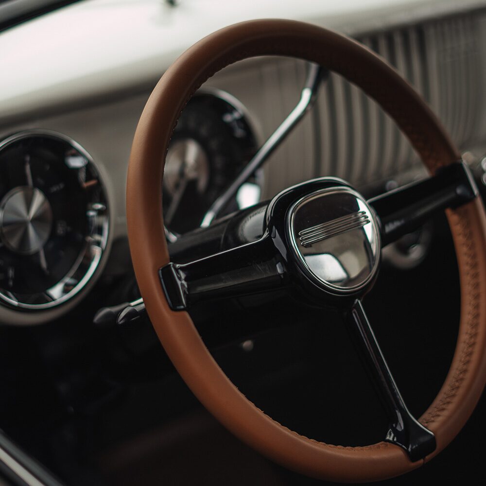 View of the Steering Wheel and Dashboard of a Blue 1955 Chevy Pickup Truck Seen Through the Driver's Side Window